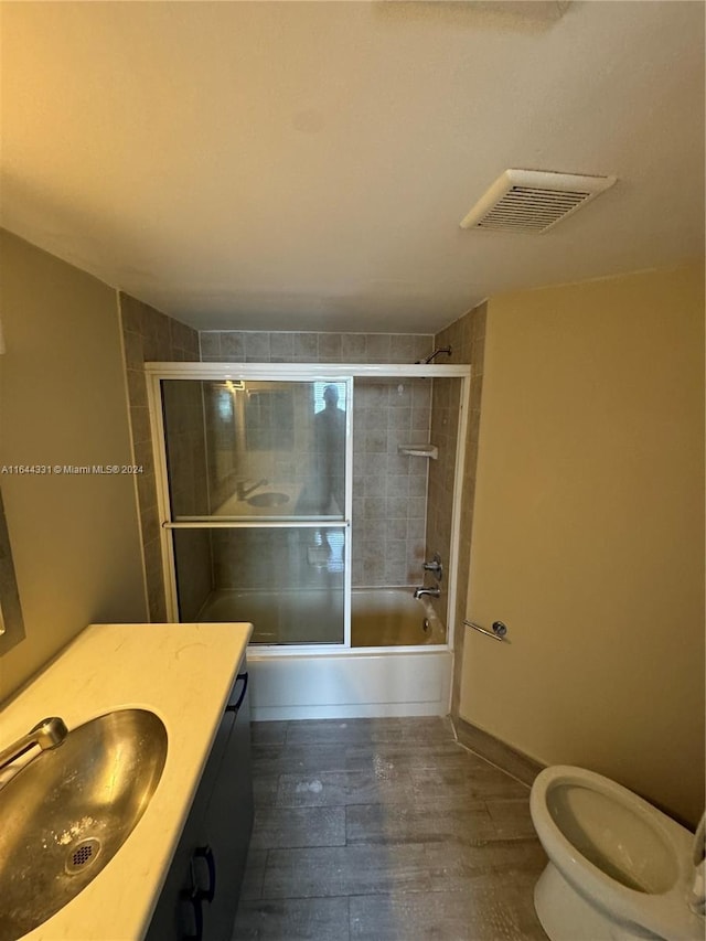 full bath with visible vents, baseboards, toilet, enclosed tub / shower combo, and vanity