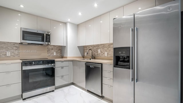 kitchen with stainless steel appliances, tasteful backsplash, sink, and white cabinets