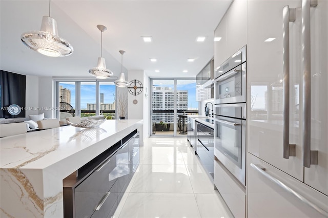 kitchen featuring decorative light fixtures, a wall of windows, refrigerator, and oven