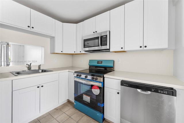 kitchen with sink, stainless steel appliances, white cabinets, and light tile patterned floors