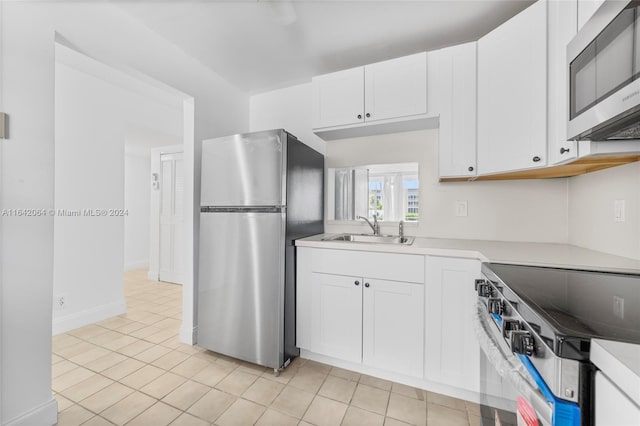 kitchen featuring appliances with stainless steel finishes, light tile patterned flooring, sink, and white cabinetry