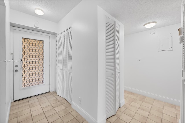 hallway with a textured ceiling, light tile patterned flooring, and electric panel