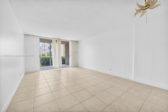 tiled empty room with ceiling fan and a textured ceiling