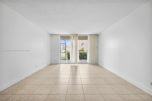 tiled spare room with a textured ceiling and floor to ceiling windows