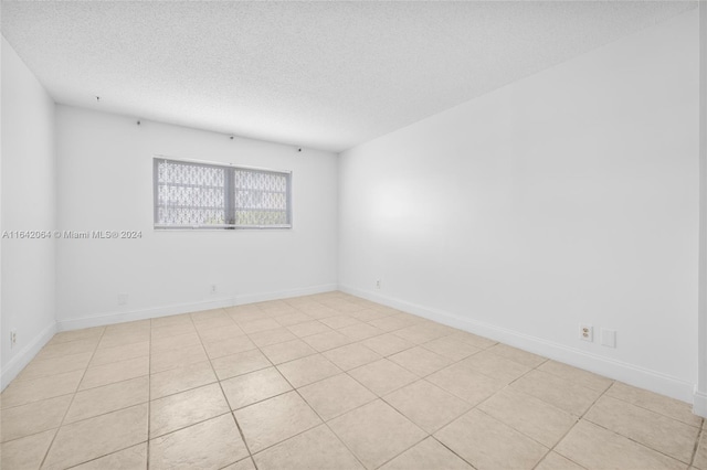 empty room featuring light tile patterned floors and a textured ceiling