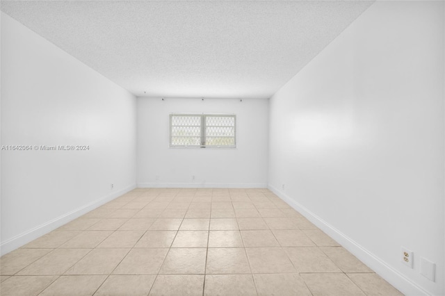 tiled spare room featuring a textured ceiling