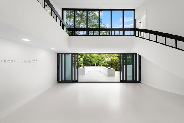 unfurnished living room featuring a healthy amount of sunlight and a high ceiling