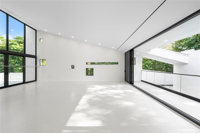 unfurnished room with expansive windows, a healthy amount of sunlight, and a high ceiling