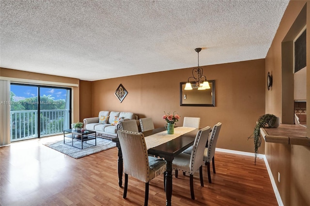 dining room with hardwood / wood-style floors, a textured ceiling, and a notable chandelier