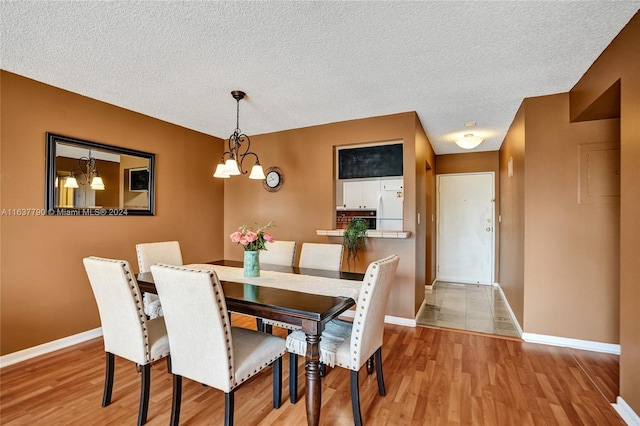 dining room with a chandelier, a textured ceiling, and light wood-type flooring