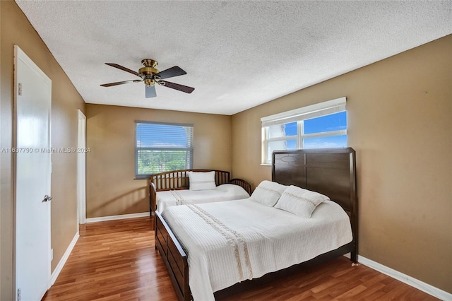 bedroom featuring ceiling fan, wood-type flooring, and a textured ceiling