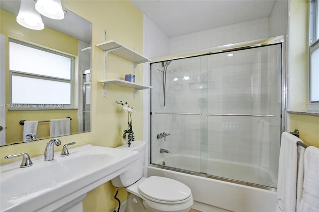 full bathroom featuring bath / shower combo with glass door, toilet, and sink