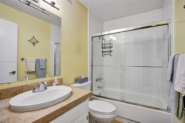 full bathroom featuring vanity, bath / shower combo with glass door, and toilet