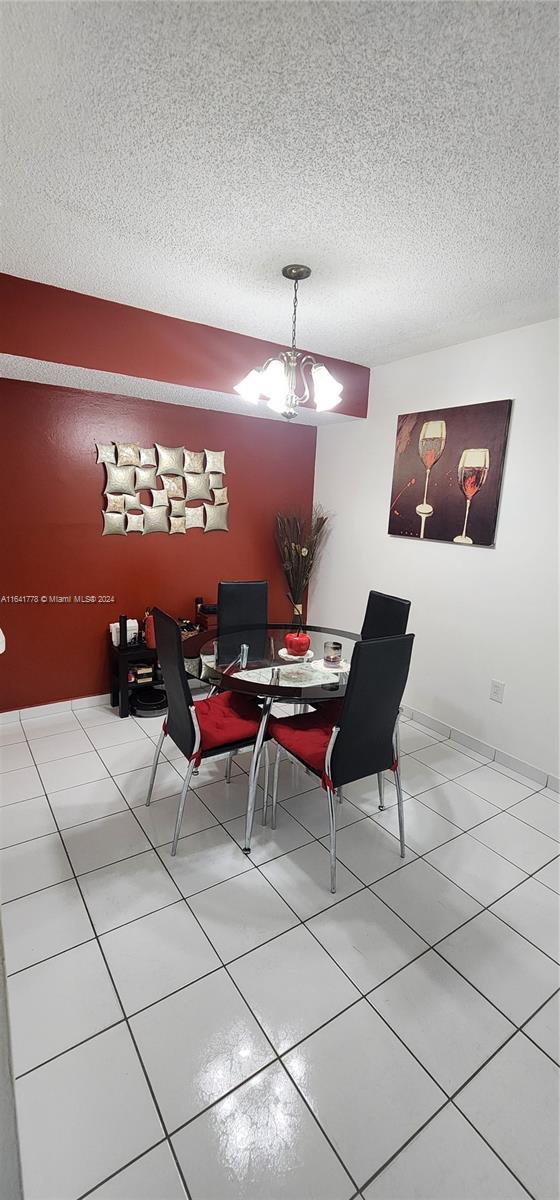 dining area featuring a notable chandelier, a textured ceiling, and tile patterned flooring