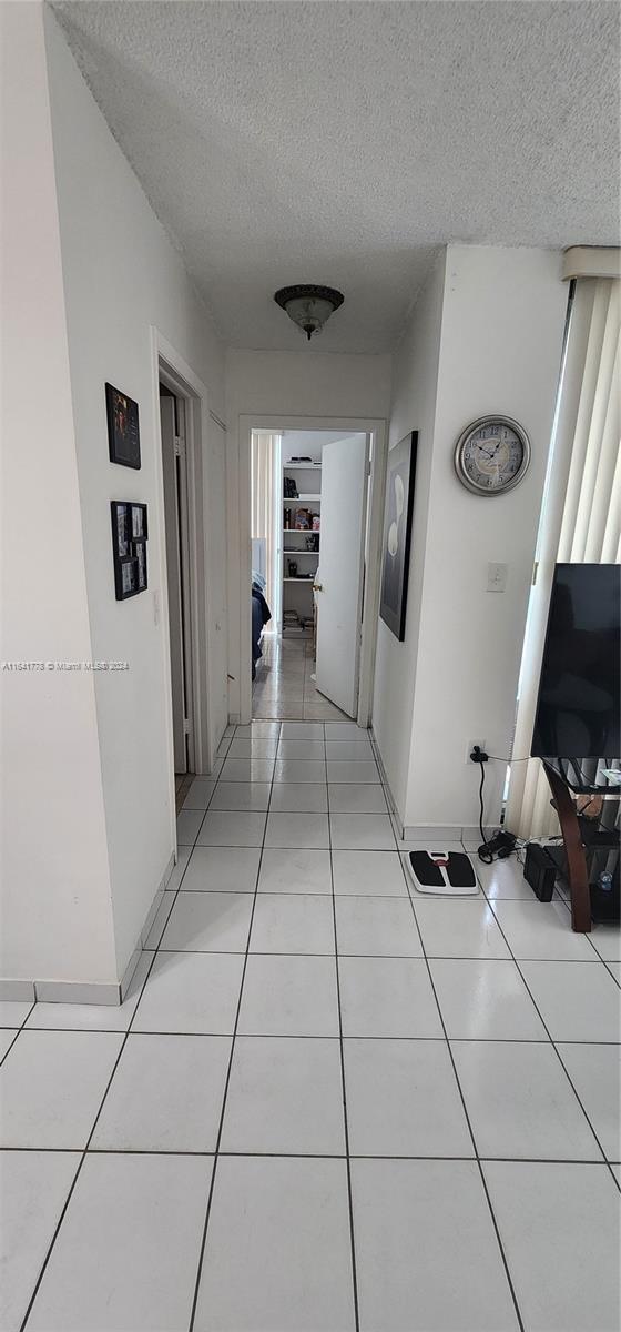 corridor featuring light tile patterned floors and a textured ceiling