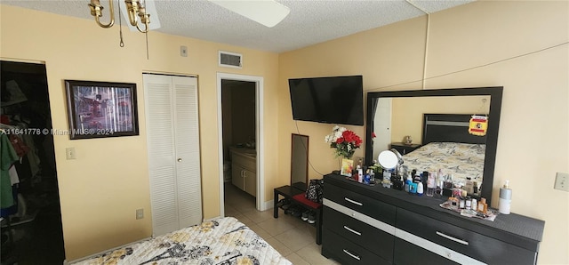 bedroom featuring light tile patterned flooring, visible vents, a textured ceiling, and a closet