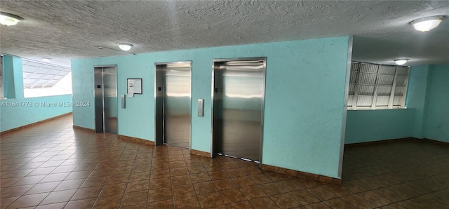 unfurnished room with tile patterned flooring, elevator, and a textured ceiling