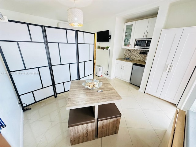 kitchen featuring pendant lighting, sink, white cabinetry, backsplash, and stainless steel appliances