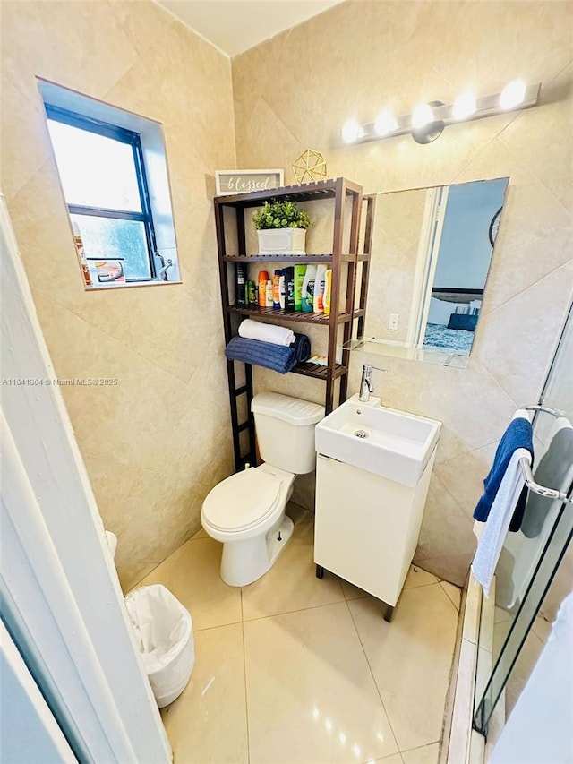 bathroom with tile patterned floors, toilet, and tile walls