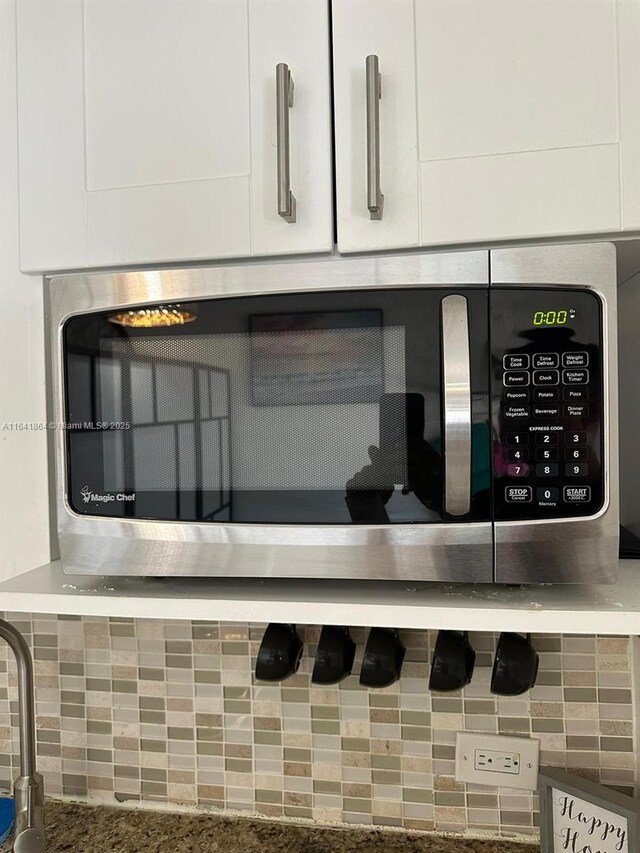 details featuring tasteful backsplash and white cabinets