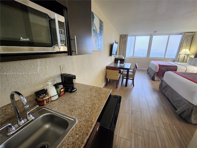 kitchen featuring light wood-type flooring, sink, and light stone counters