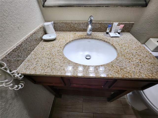 bathroom with wood-type flooring, toilet, and vanity