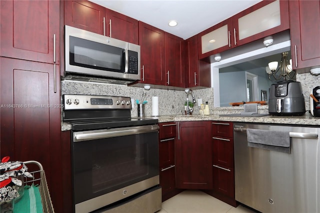 kitchen featuring decorative backsplash, light stone countertops, and appliances with stainless steel finishes