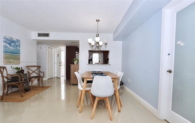 dining space featuring tile patterned floors and a chandelier