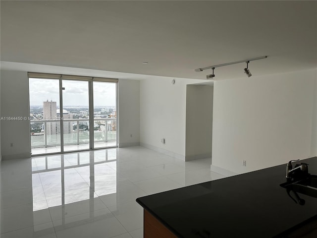 spare room with floor to ceiling windows, light tile patterned flooring, and rail lighting