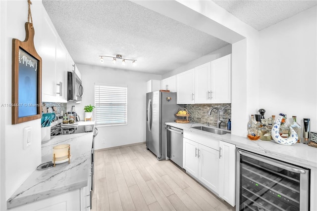 kitchen featuring white cabinets, appliances with stainless steel finishes, wine cooler, and sink