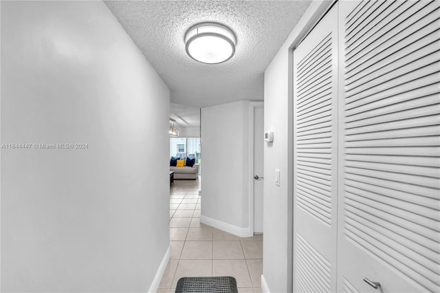 corridor with light tile patterned floors and a textured ceiling