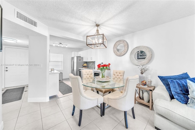 tiled dining area featuring a textured ceiling and an inviting chandelier