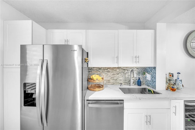 kitchen with backsplash, stainless steel appliances, white cabinetry, and sink