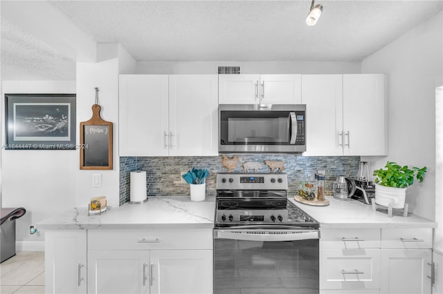 kitchen with light stone countertops, light tile patterned flooring, a textured ceiling, white cabinets, and appliances with stainless steel finishes