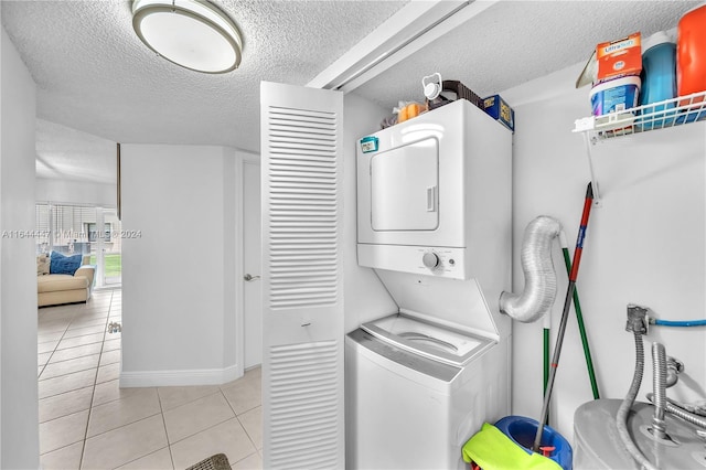 laundry area featuring light tile patterned floors, a textured ceiling, and stacked washer and clothes dryer