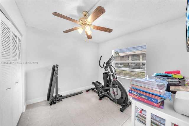 workout area with ceiling fan, light tile patterned floors, and a textured ceiling