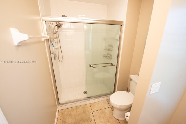 bathroom featuring toilet, an enclosed shower, and tile patterned flooring