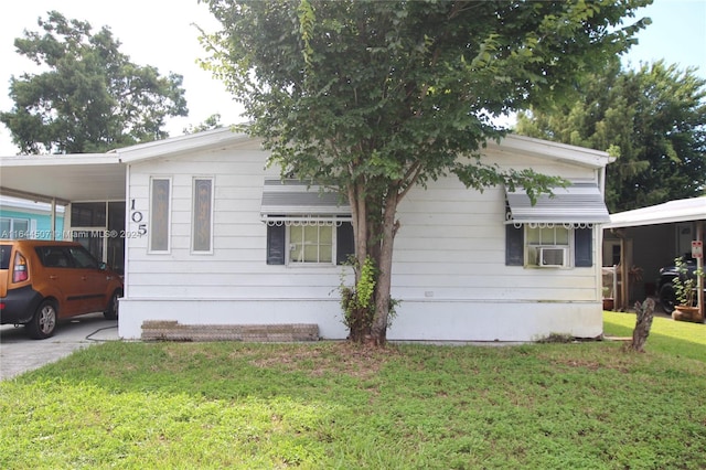 view of front of property with a front lawn, a carport, and cooling unit