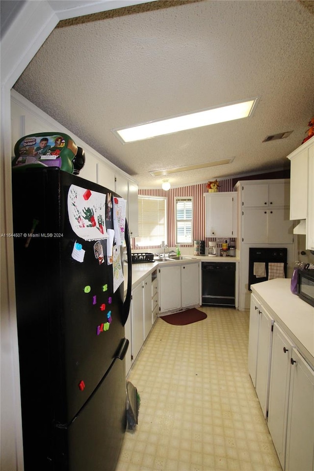 kitchen featuring lofted ceiling, a textured ceiling, light tile patterned floors, black appliances, and white cabinets