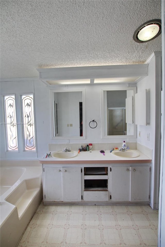 bathroom featuring a textured ceiling, a bathtub, double sink vanity, and tile patterned floors