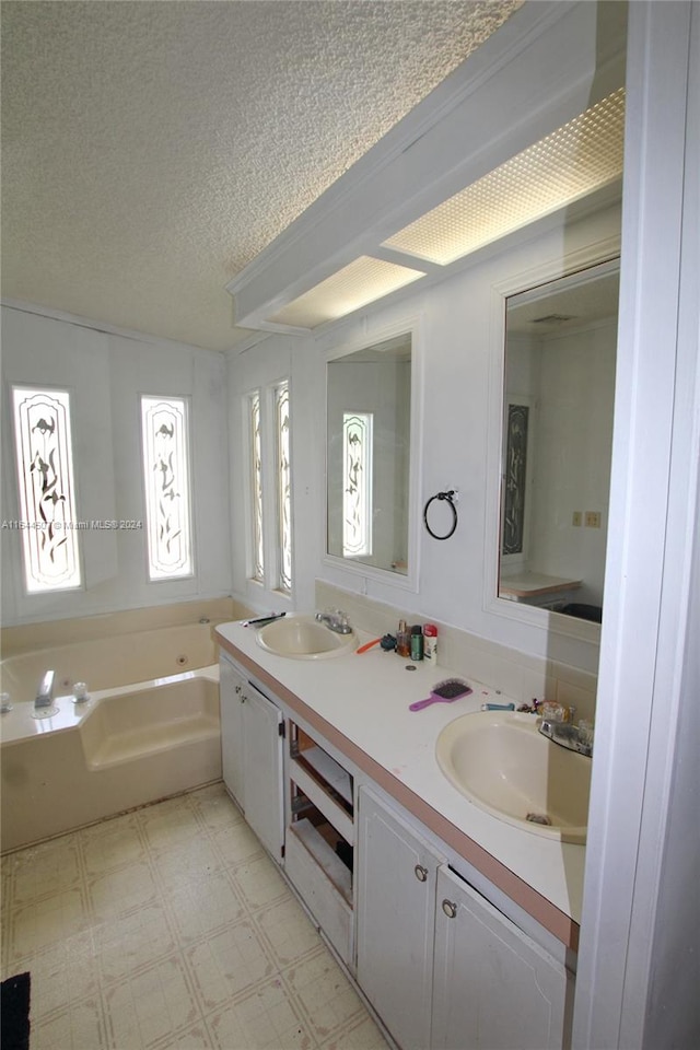 bathroom featuring a textured ceiling, double vanity, a bathtub, and tile patterned flooring