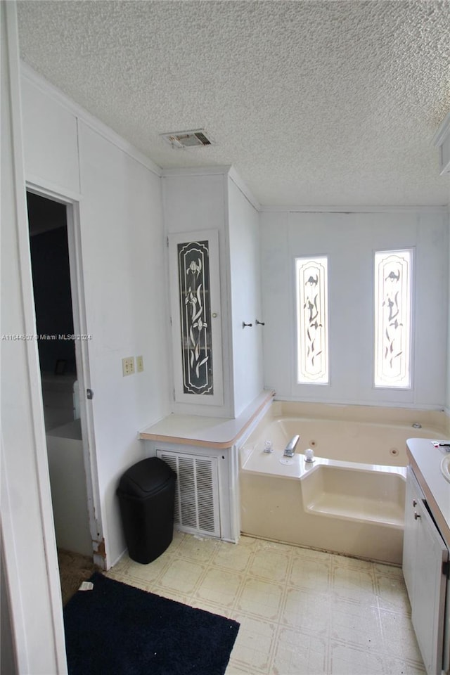 bathroom featuring tile patterned floors, a tub, a textured ceiling, and vanity