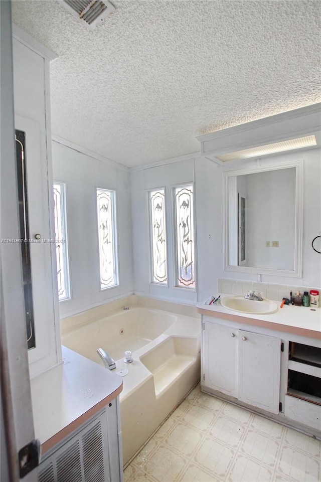 bathroom featuring tile patterned flooring, a tub to relax in, a textured ceiling, and vanity