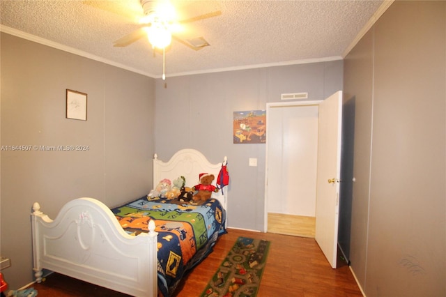 bedroom with a textured ceiling, ceiling fan, crown molding, and wood-type flooring