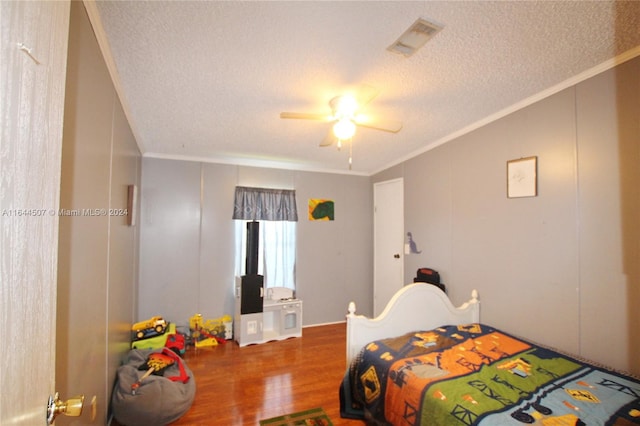 bedroom with ceiling fan, wood-type flooring, a textured ceiling, and ornamental molding