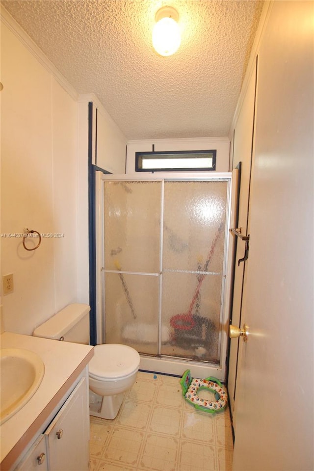 bathroom featuring tile patterned floors, a textured ceiling, vanity, toilet, and a shower with door