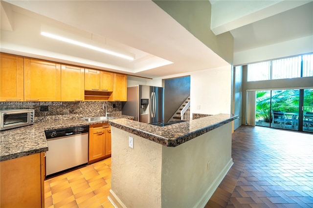 kitchen featuring appliances with stainless steel finishes, backsplash, sink, a raised ceiling, and kitchen peninsula