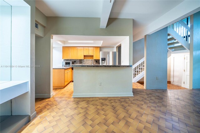 kitchen featuring stainless steel fridge with ice dispenser, backsplash, light brown cabinetry, and beam ceiling