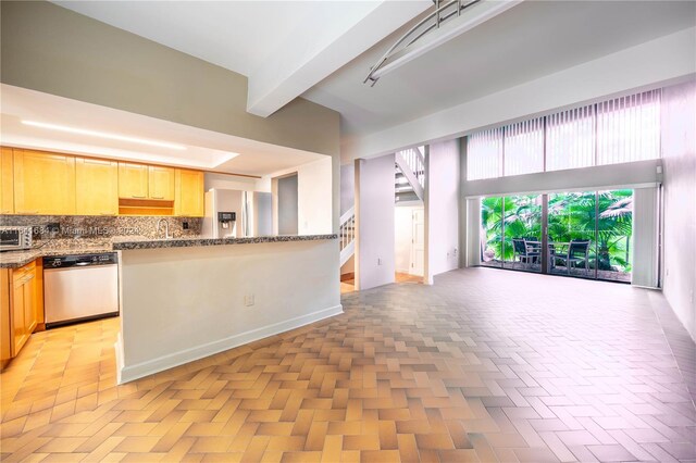 kitchen featuring beamed ceiling, stainless steel appliances, tasteful backsplash, and light brown cabinetry