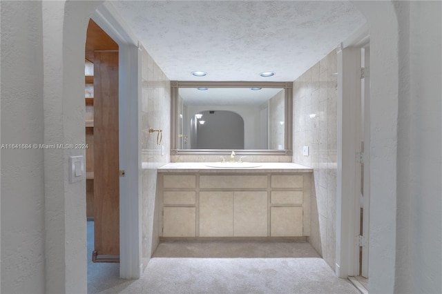 bathroom with vanity, a textured ceiling, and a textured wall